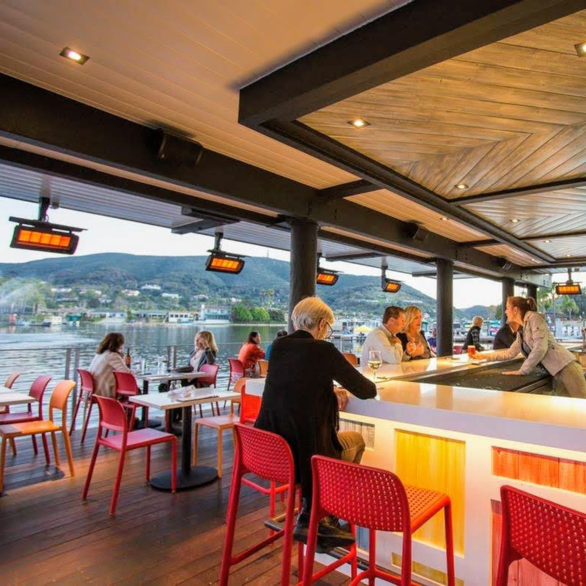 Calefactores Bromic Tungsten 500 instalados en terraza de restaurante junto al lago, con clientes disfrutando del ambiente