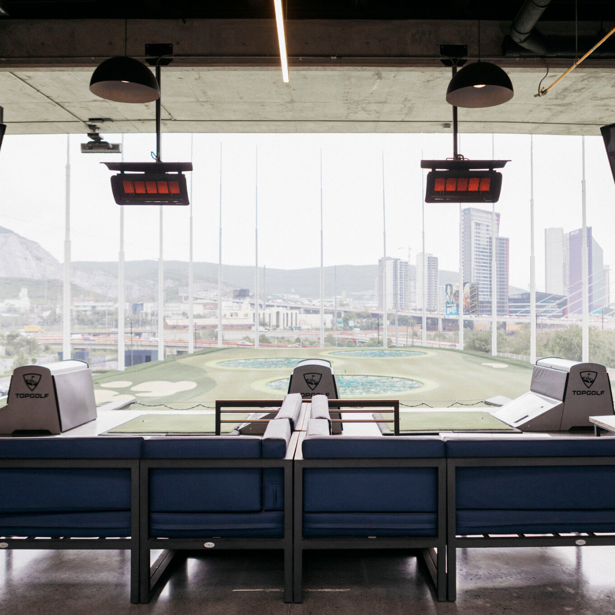 Calefactores Bromic Tungsten 500 instalados en techo de terraza en Topgolf con vista a campo, calefacción profesional para espacios comerciales